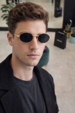 Luxury oval sunglasses gold metal frame black lens side view